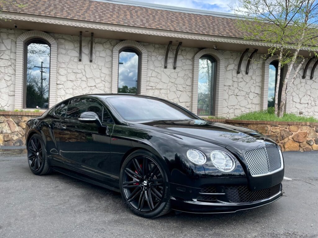 Black luxury car parked near building.