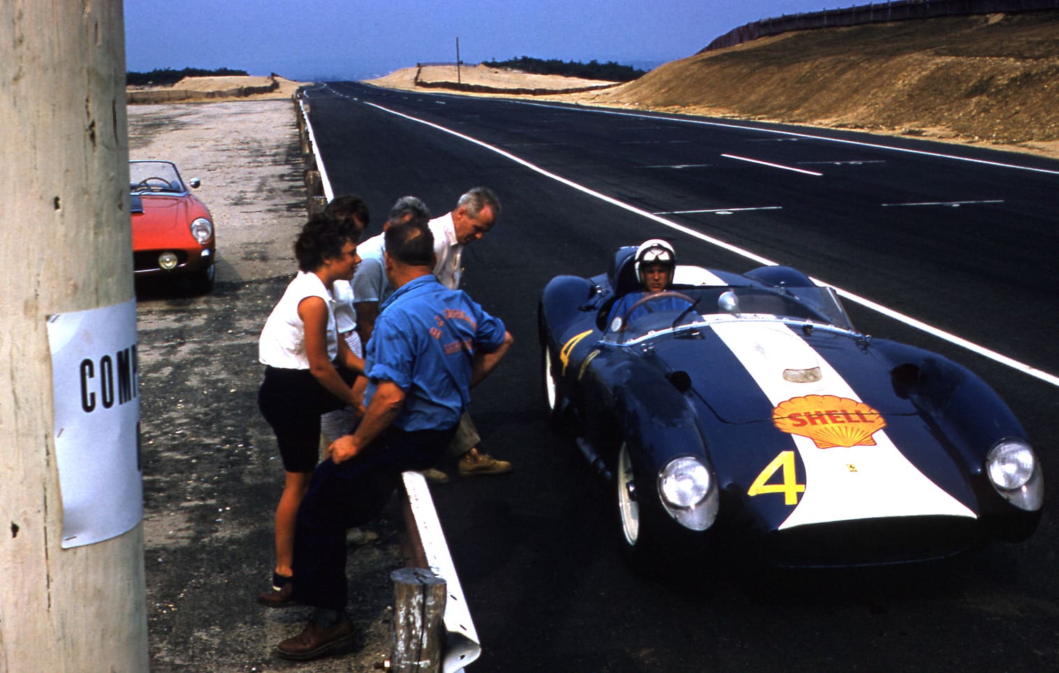 Race car stopped on track with spectators.