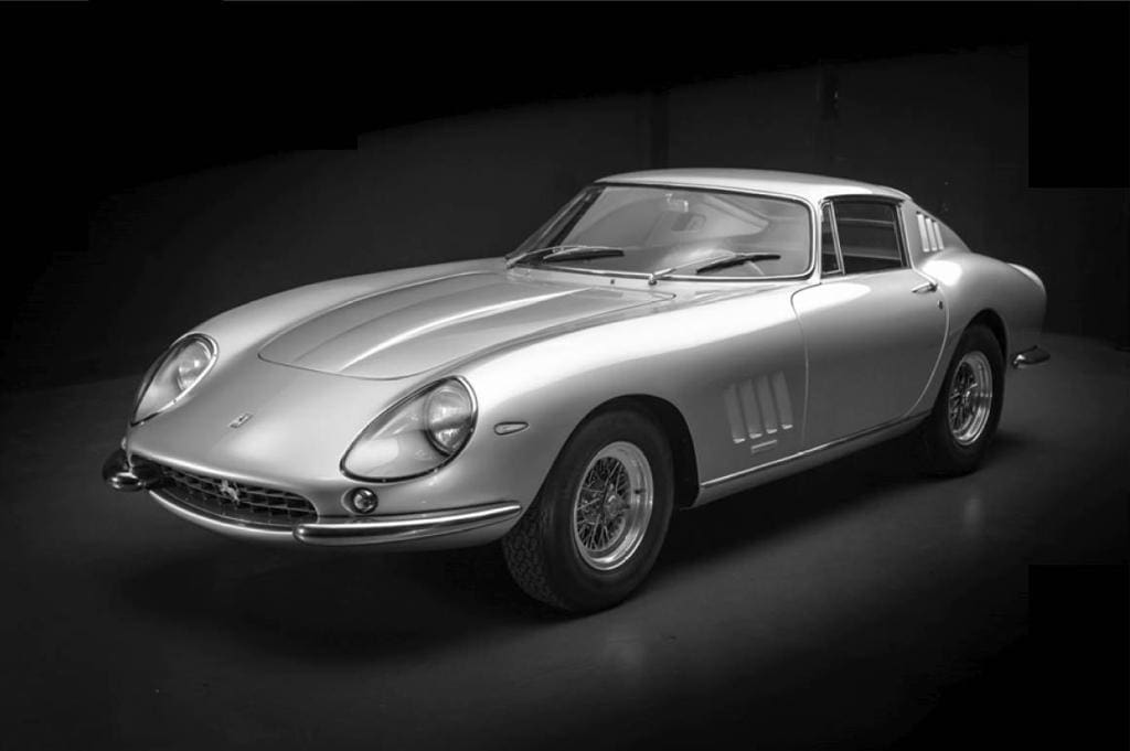Silver classic sports car on dark background.