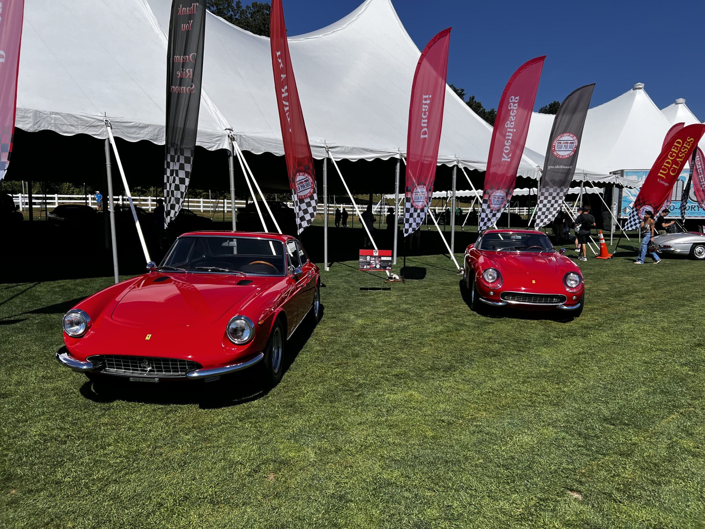 Two red classic cars under tents.