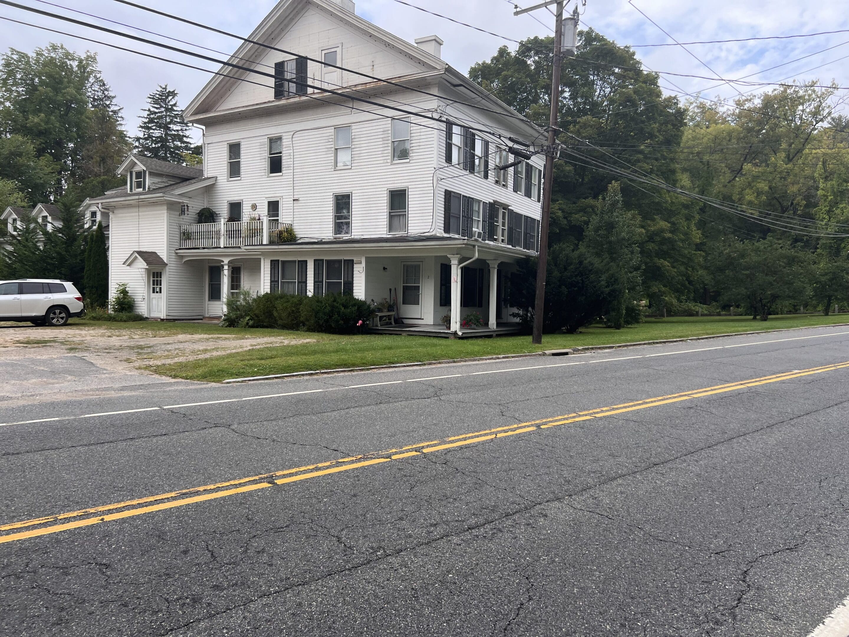 White house by a roadside with trees.