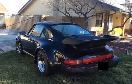 Black classic sports car parked outside house.