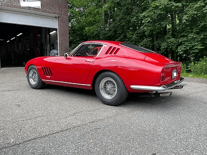 Red vintage car parked outside garage