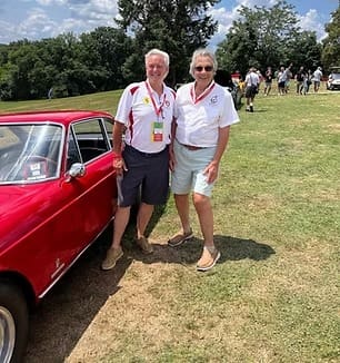 Two men posing by classic red car