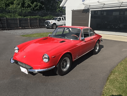 Red vintage sports car parked outside.