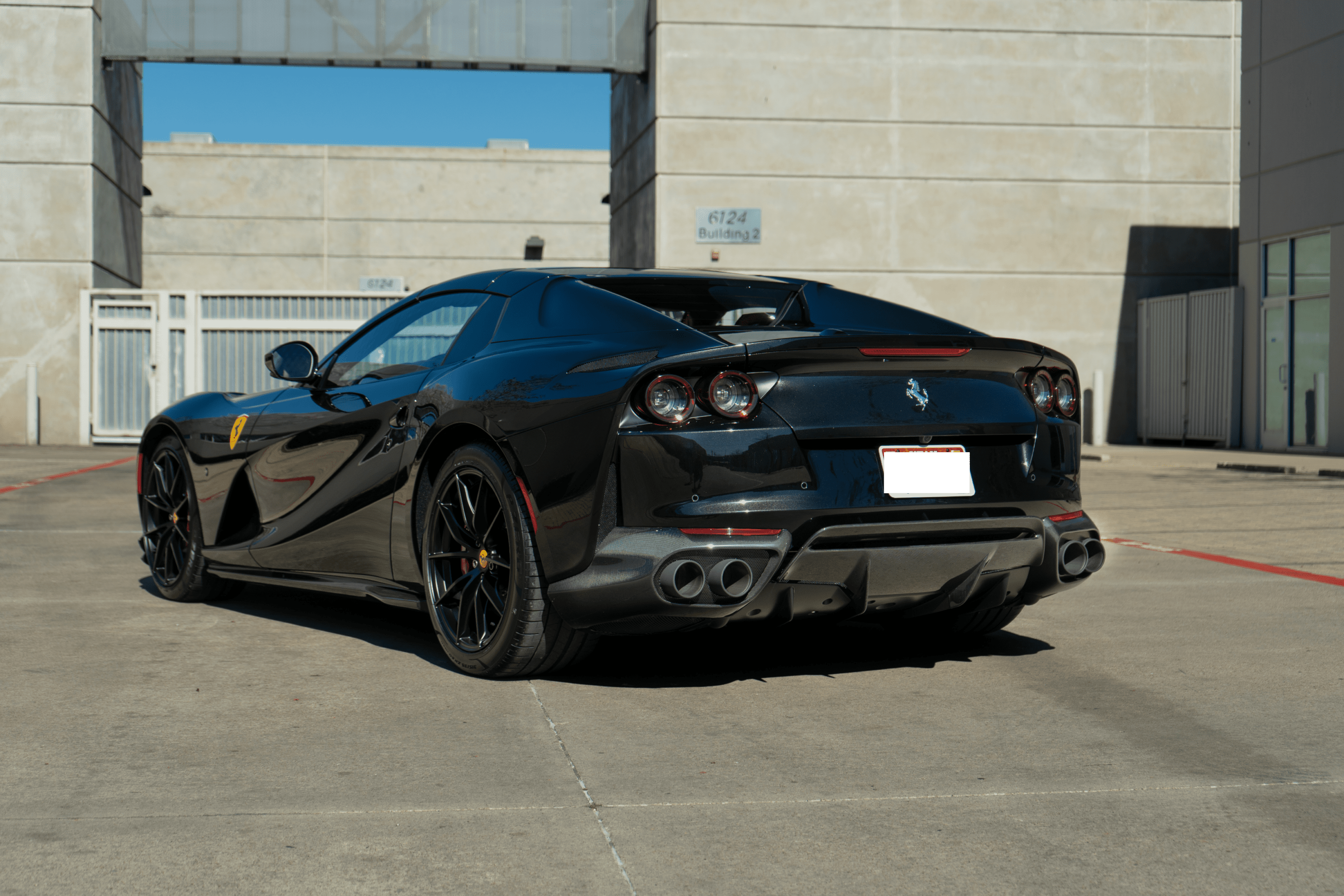 Black Ferrari sports car parked in concrete lot