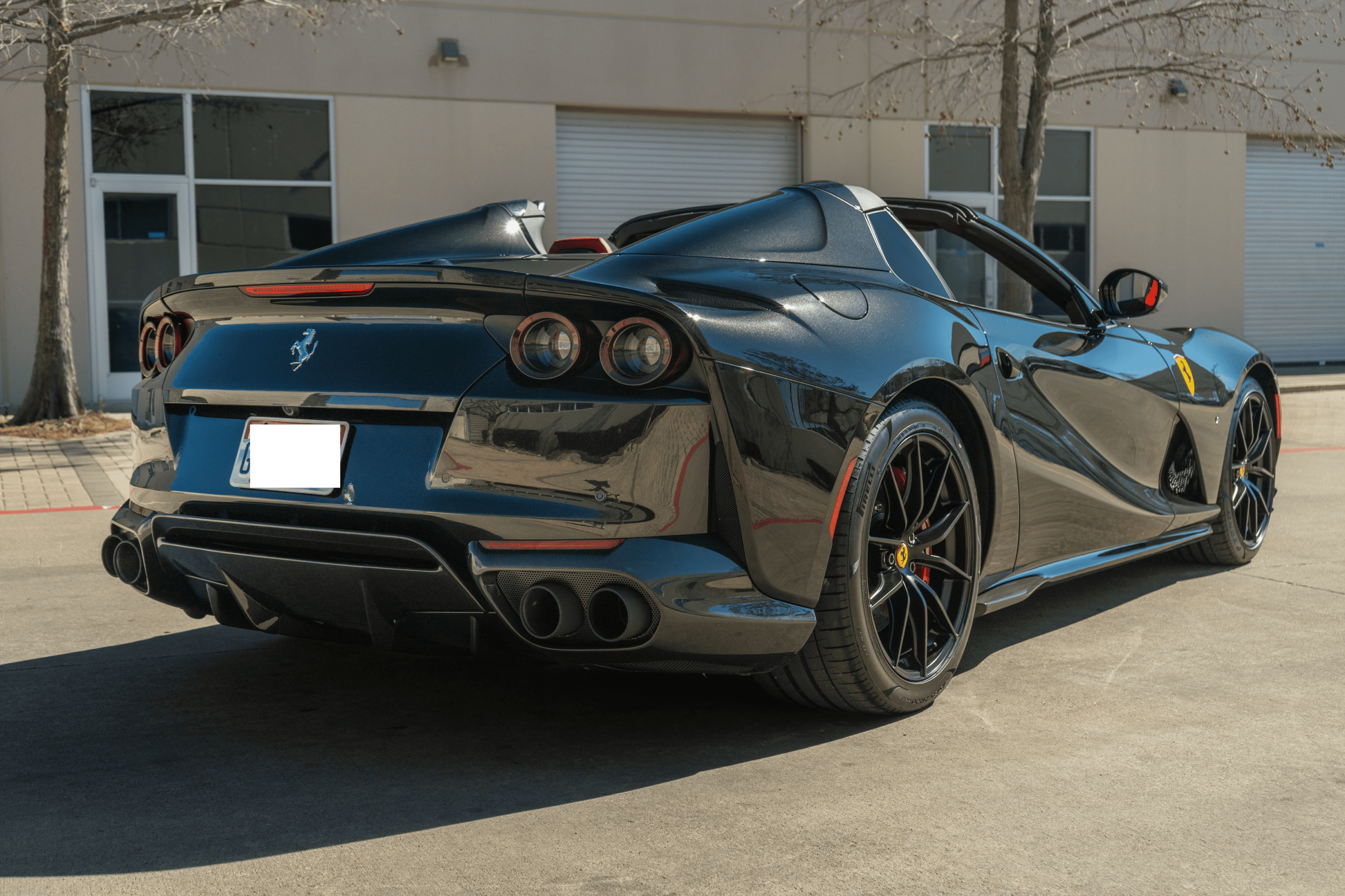 Black Ferrari convertible parked outside industrial building